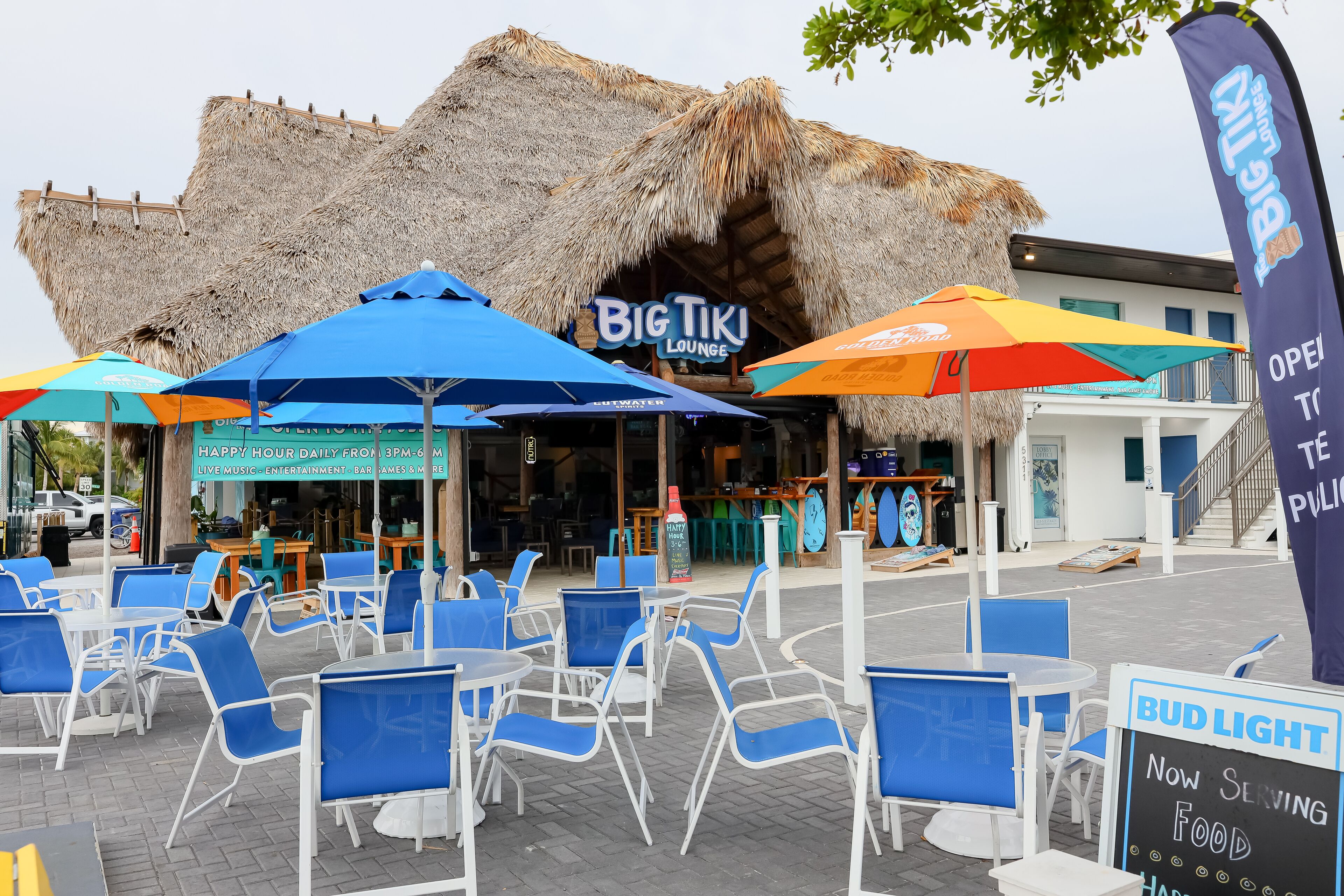 Zona exterior amb seients blaus i ombrelles al Big Tiki Lounge.