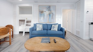 Un salon moderne avec un canapé bleu, une table basse en bois et une bibliothèque.