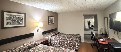 Een hotelkamer met twee bedden, een bureau, een stoel, een televisie en een spiegel.