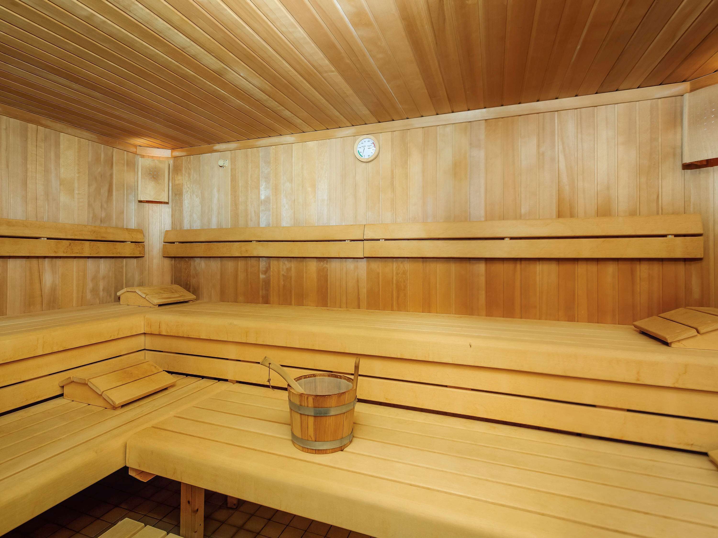A sauna with wooden benches and a wooden bucket.