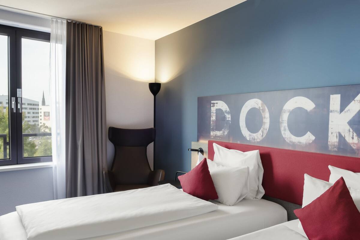 Ein Hotelzimmer mit Bett, Stuhl, Lampe und einem großen Wandschild.