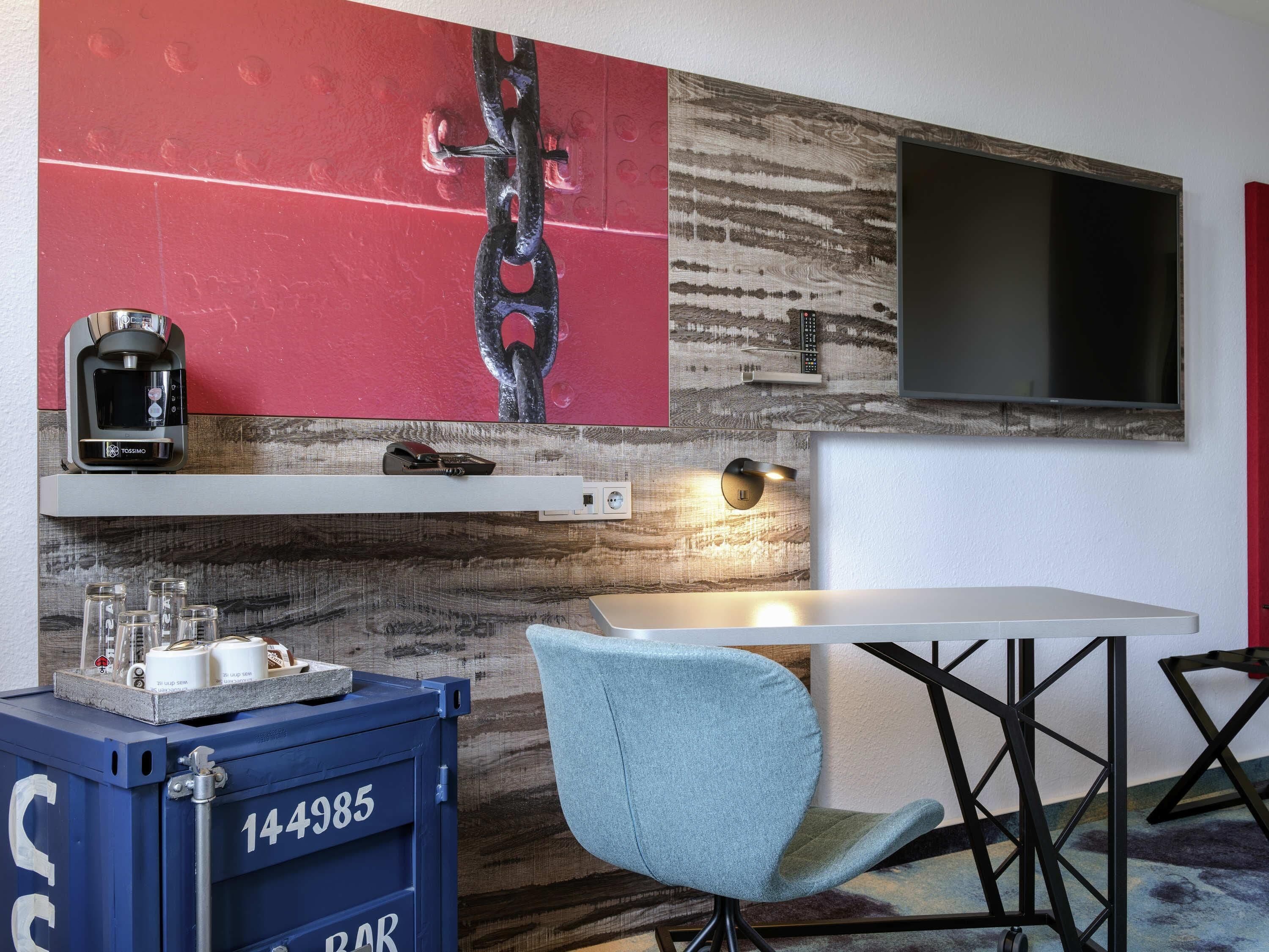 A modern room with a TV, a coffee machine, a bar, and a seating area.