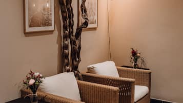 A room with two wicker chairs, a small table, and a wall-mounted light fixture.