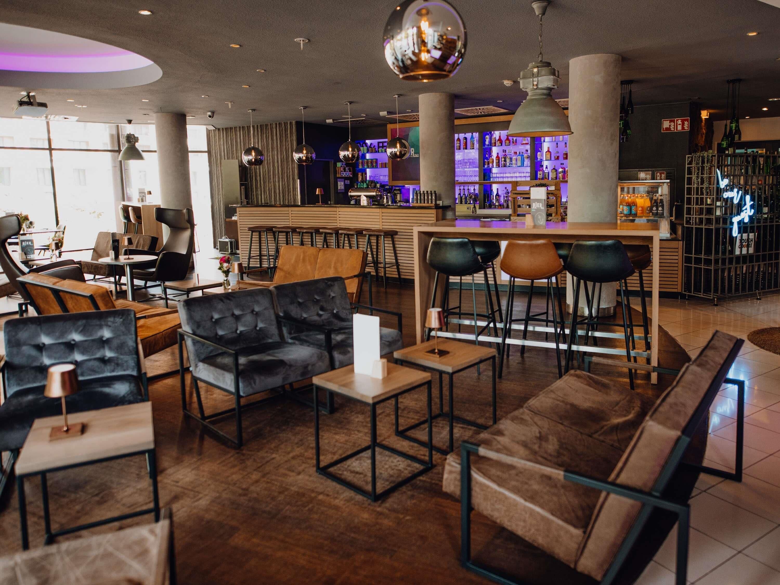 A modern bar area with leather seating, a bar counter, and a variety of bottles.