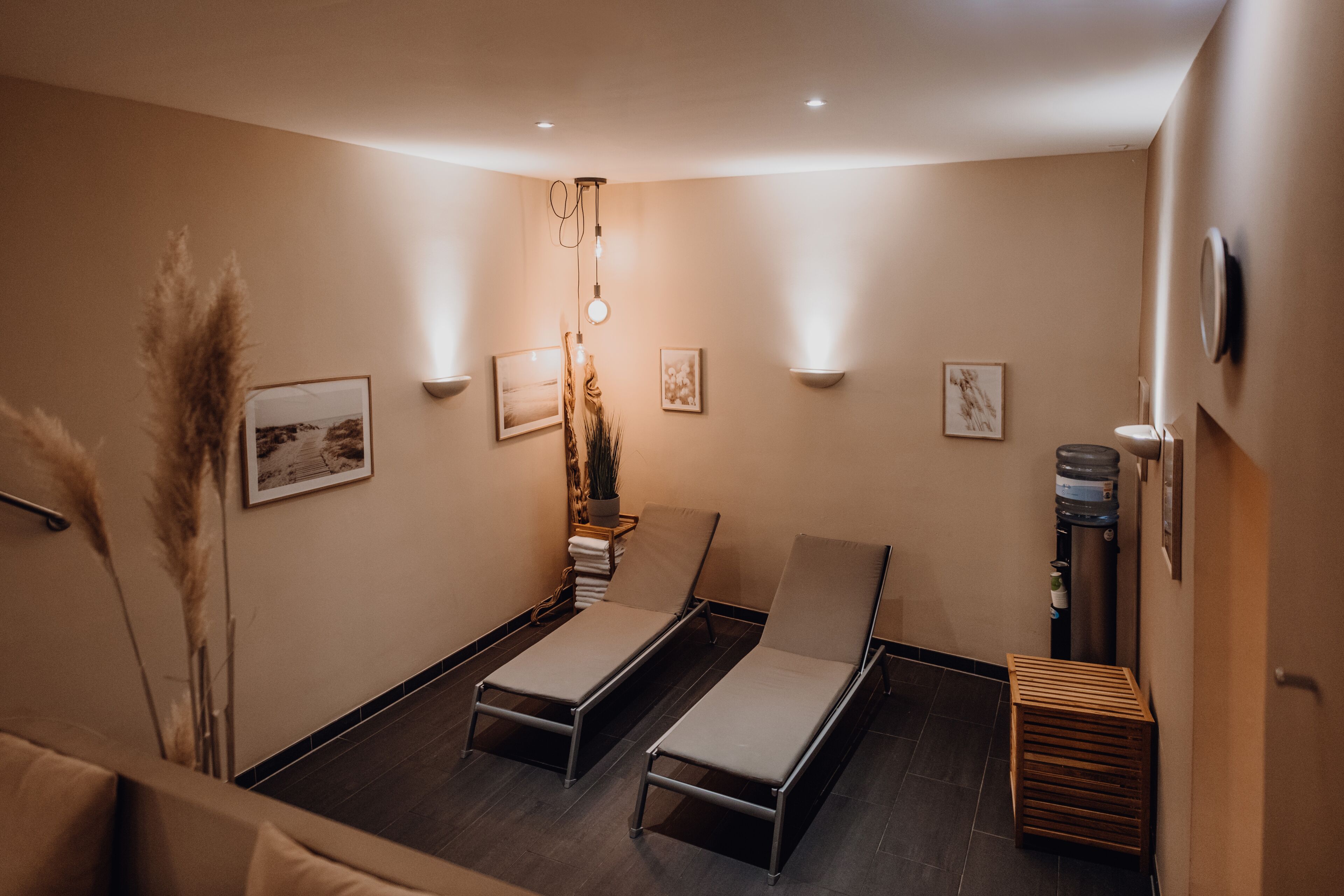 Un cuarto de spa con dos sillones reclinables, una mesita con una planta e iluminación en la pared.