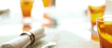 A table with a folded napkin, a fork, and a glass with a beverage.
