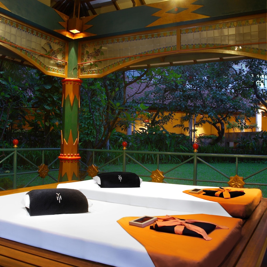 A room with a bed, a wooden bench, and a decorative pillar.