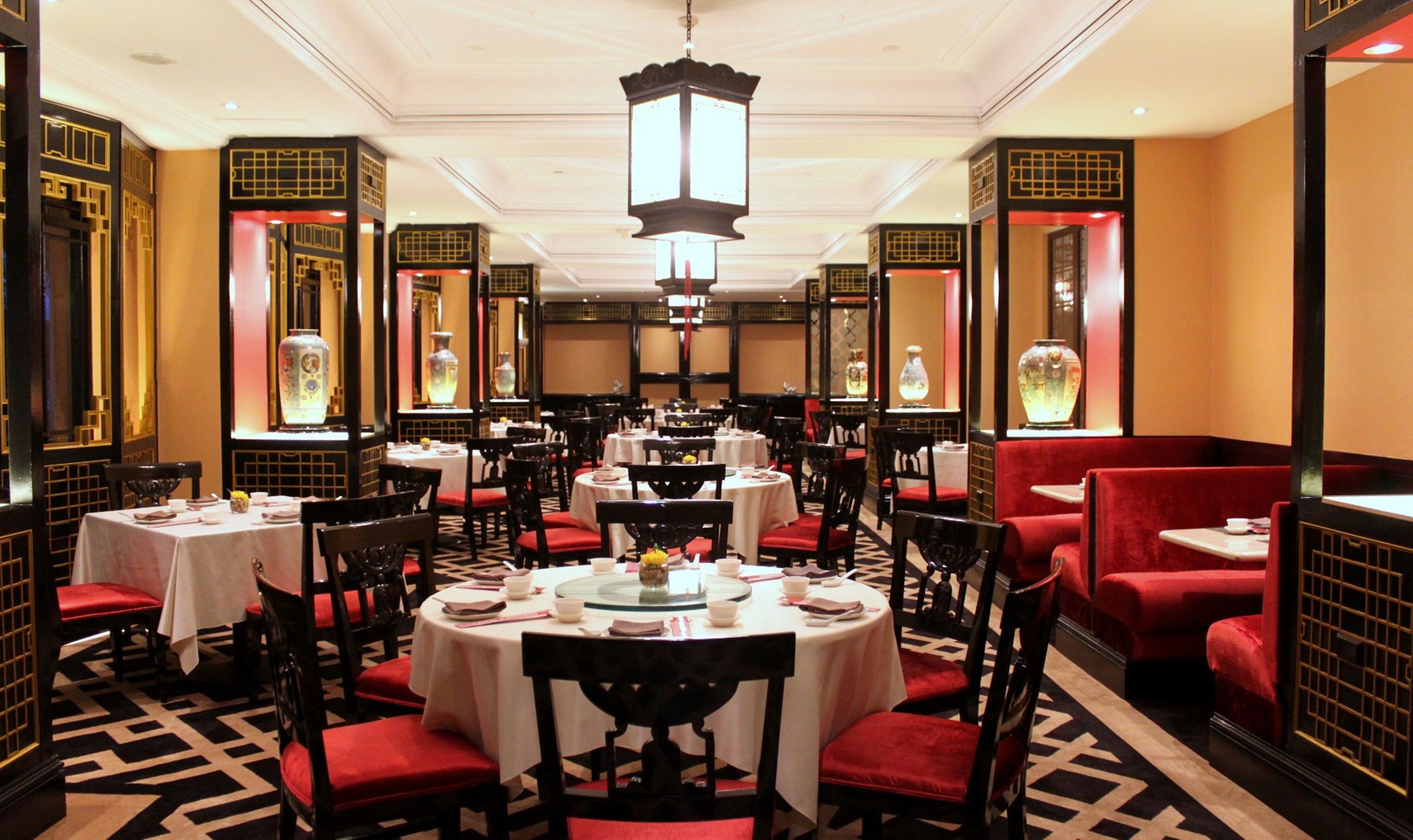 A restaurant with round tables, red upholstered booths, and traditional decor.