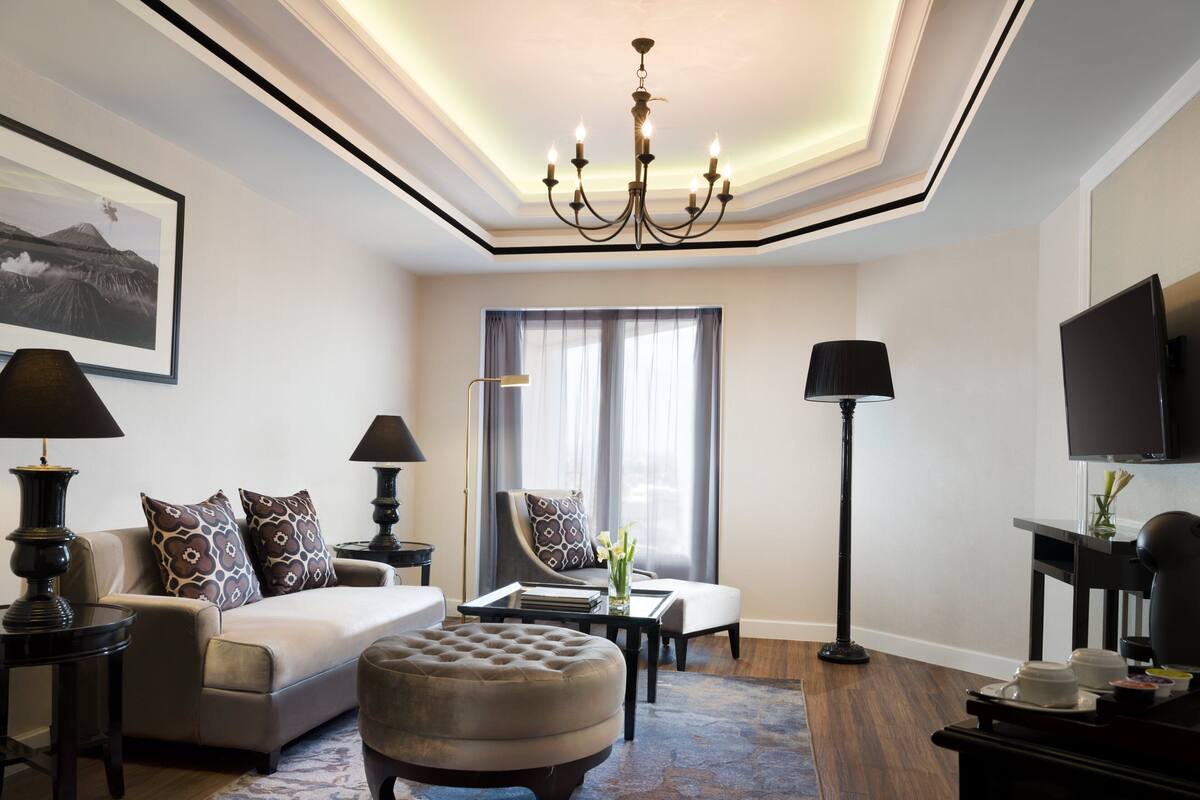 A modern living room with a sofa, ottoman, and a flat-screen TV.