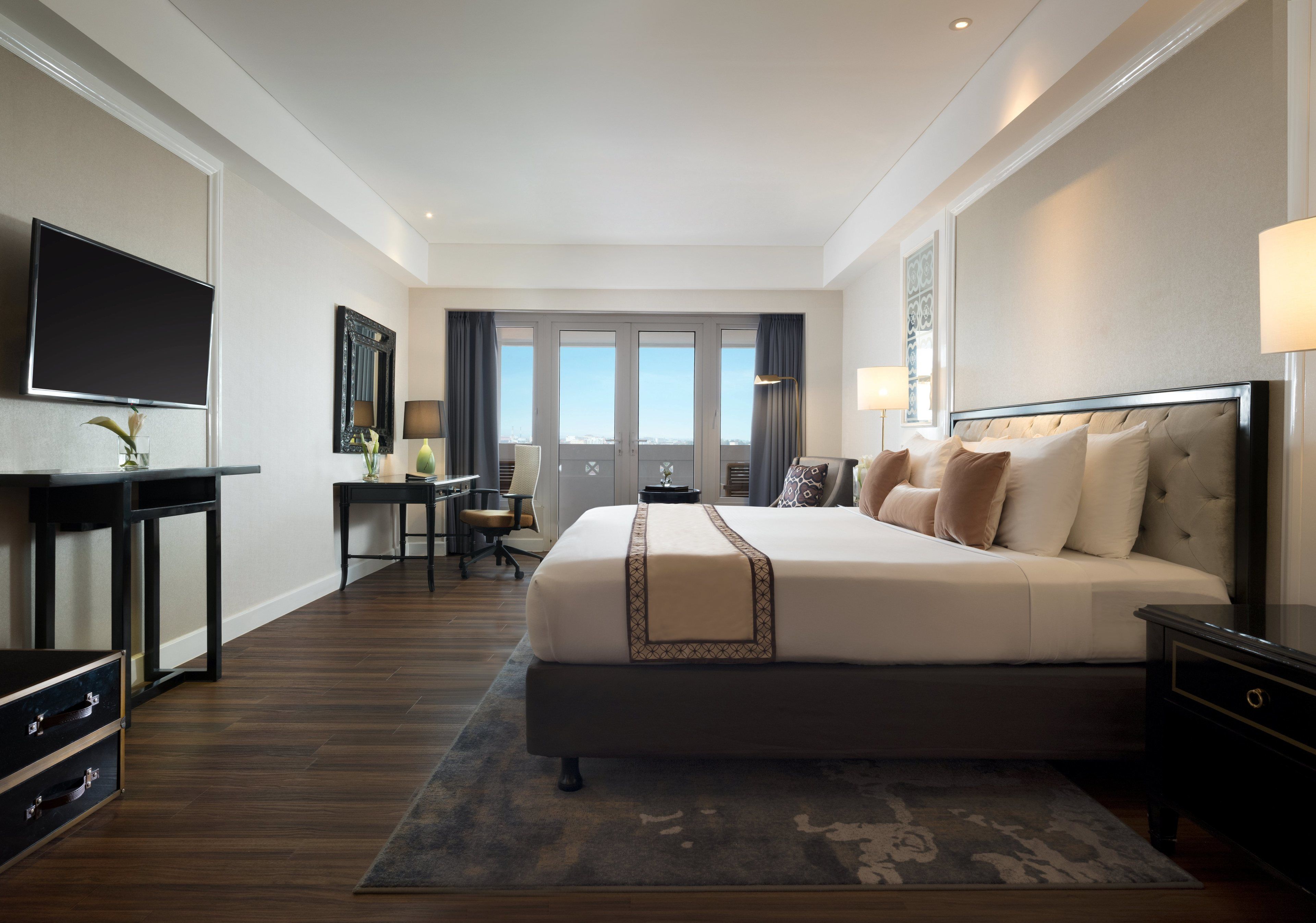 Een moderne hotelkamer met een groot bed, een bureau, een televisietoestel en uitzicht op de stad.