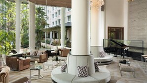 A spacious lobby with a grand piano, comfortable seating, and a view of the outdoors.