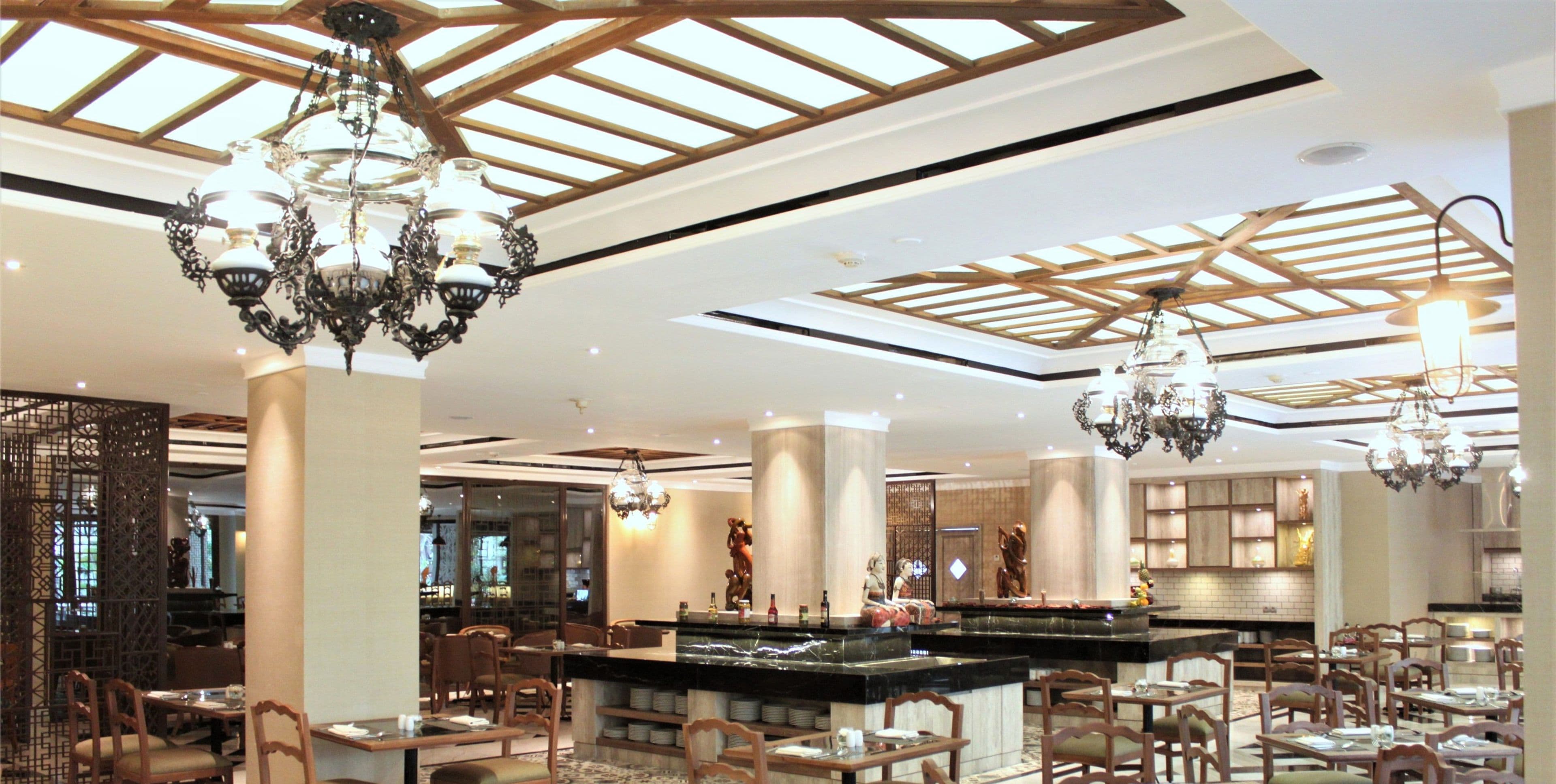 A spacious hotel lobby with high ceilings, chandeliers, and a central bar area.