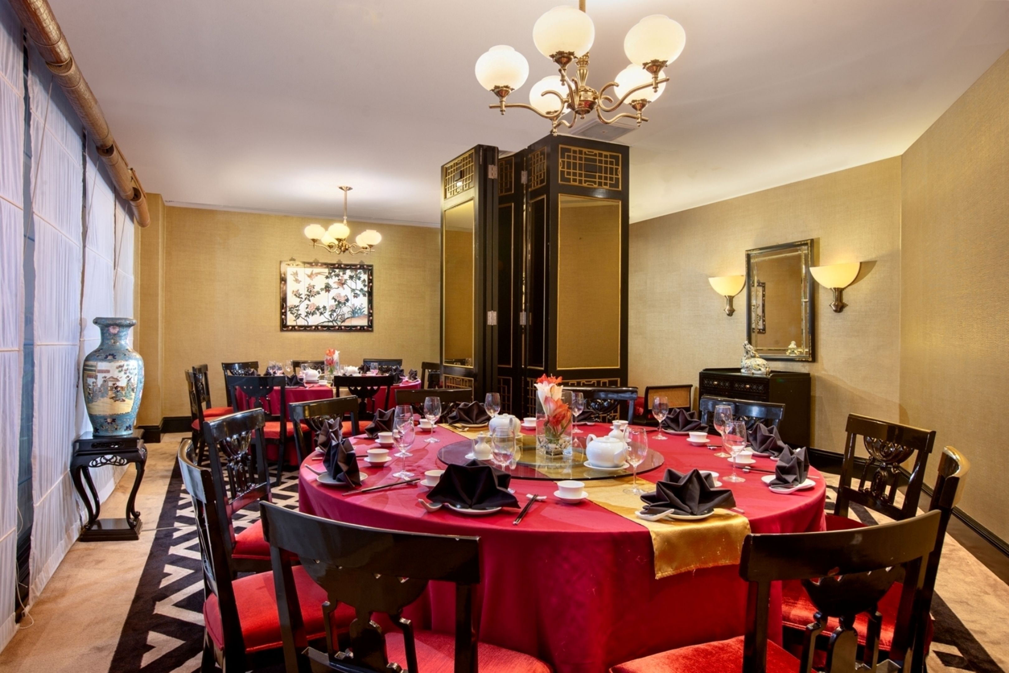 Uma sala de jantar formal com uma mesa redonda posta para uma refeição, rodeada por cadeiras.