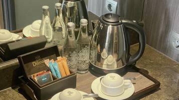 A breakfast tray with coffee pot, cups, and tea service on a marble countertop.