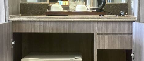 A minibar with a refrigerator, a coffee maker, and some bottles.