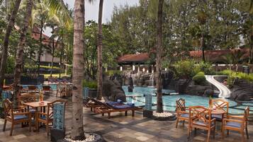 Relax by the resort pool surrounded by lush vegetation and a soothing waterfall.