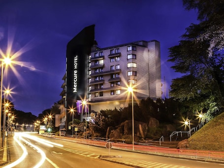 A hotel building with multiple floors, a prominent sign, and a well-lit street in the foreground.. Mercure Hotel Hagen