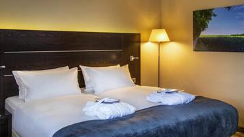 A hotel room with a large bed, a nightstand, a lamp, and a painting on the wall.