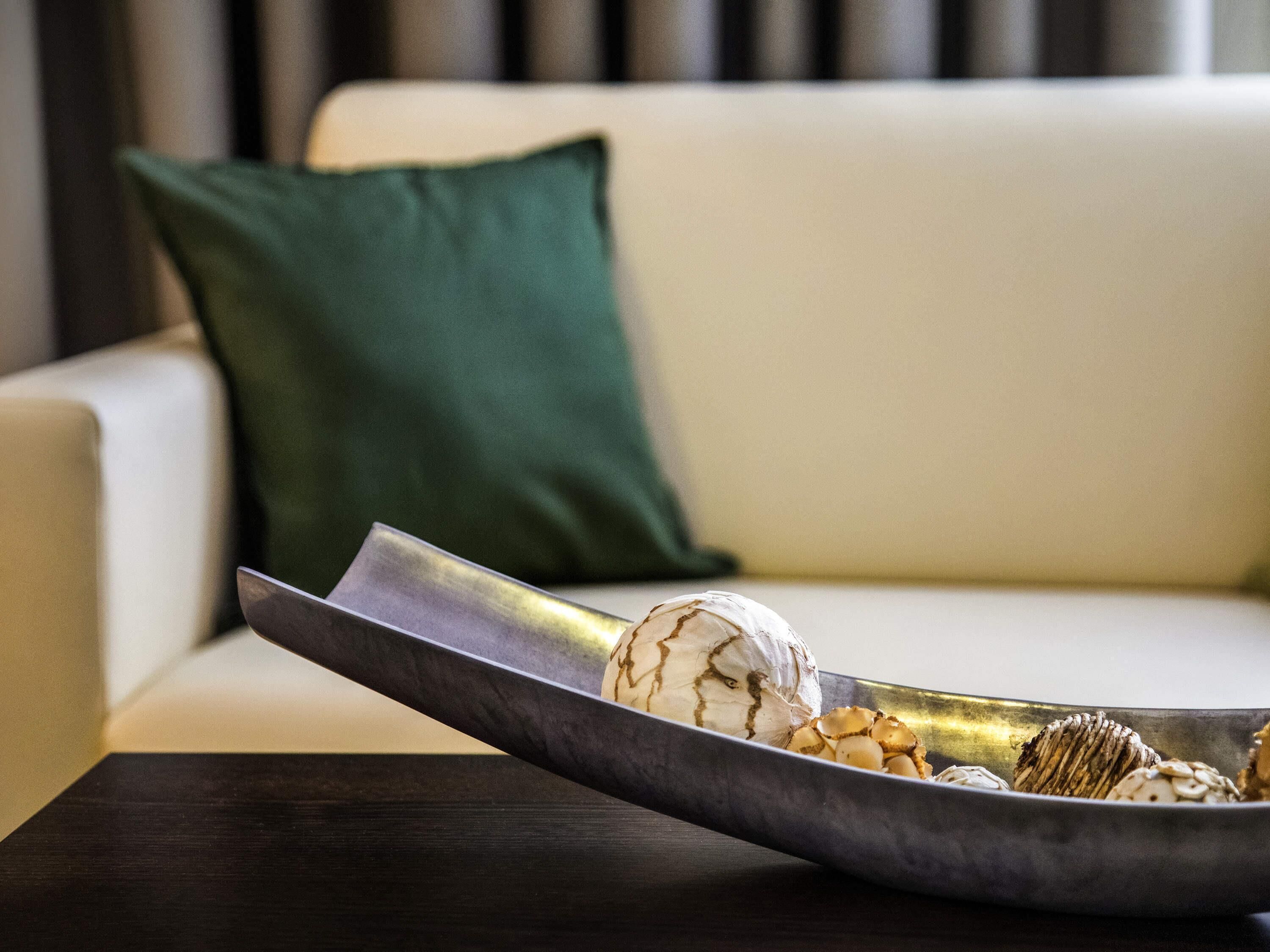 A modern living room with a sofa, a green pillow, and a tray with decorative items.