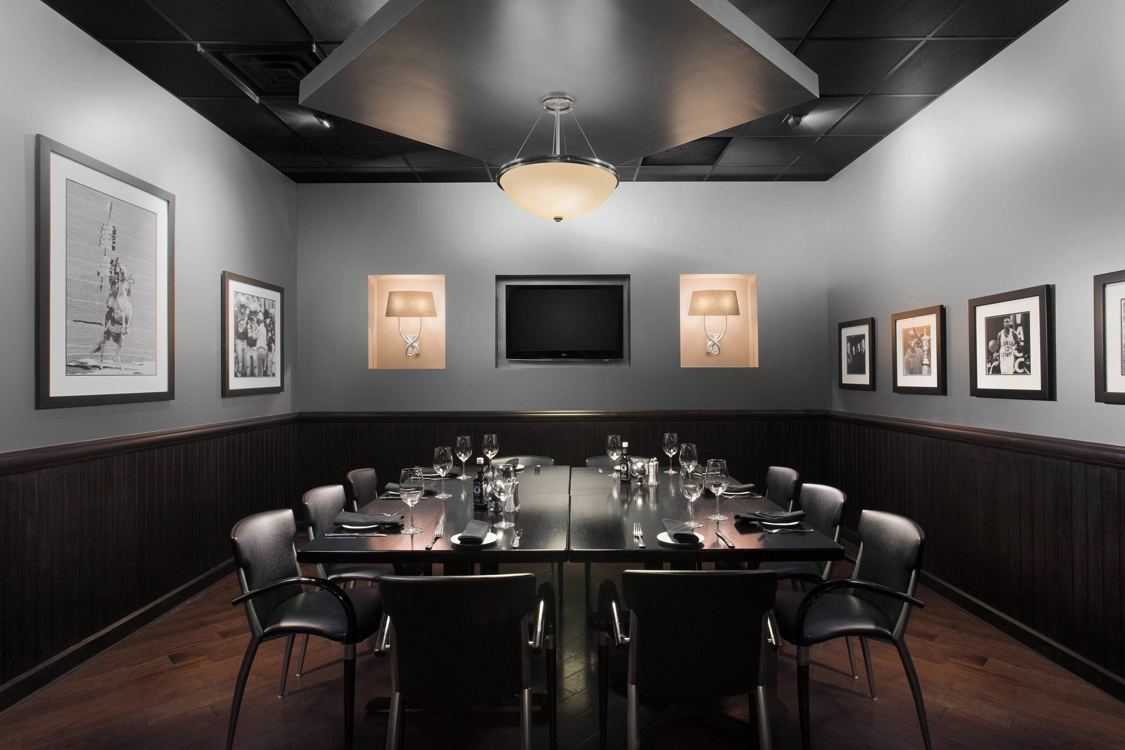 A conference room with a long table, chairs, and framed pictures on the walls.