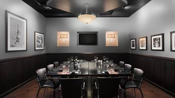 A conference room with a long table, chairs, and framed pictures on the walls.