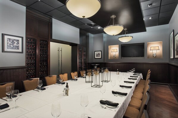 Une salle de conférence avec une longue table, des chaises et un meuble à vin.