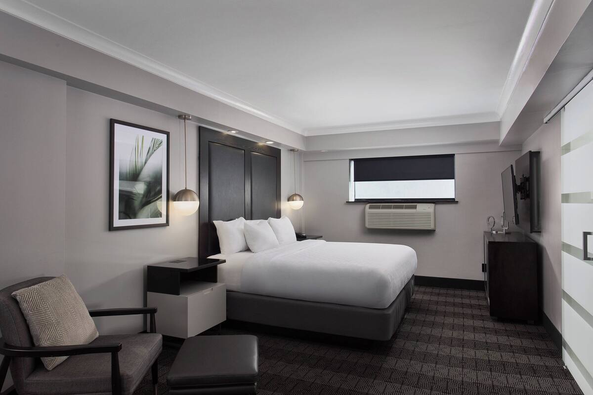 Una habitación de hotel moderna con una cama grande, un escritorio, una silla y una mesita.