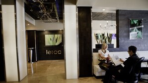 Un espace d’accueil au design moderne, comprenant un comptoir de réception, un coin salon et un grand écran affichant le nom de l’hôtel.
