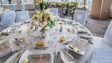 Une table ronde dressée pour un événement formel, avec un menu, des verres et des couverts.