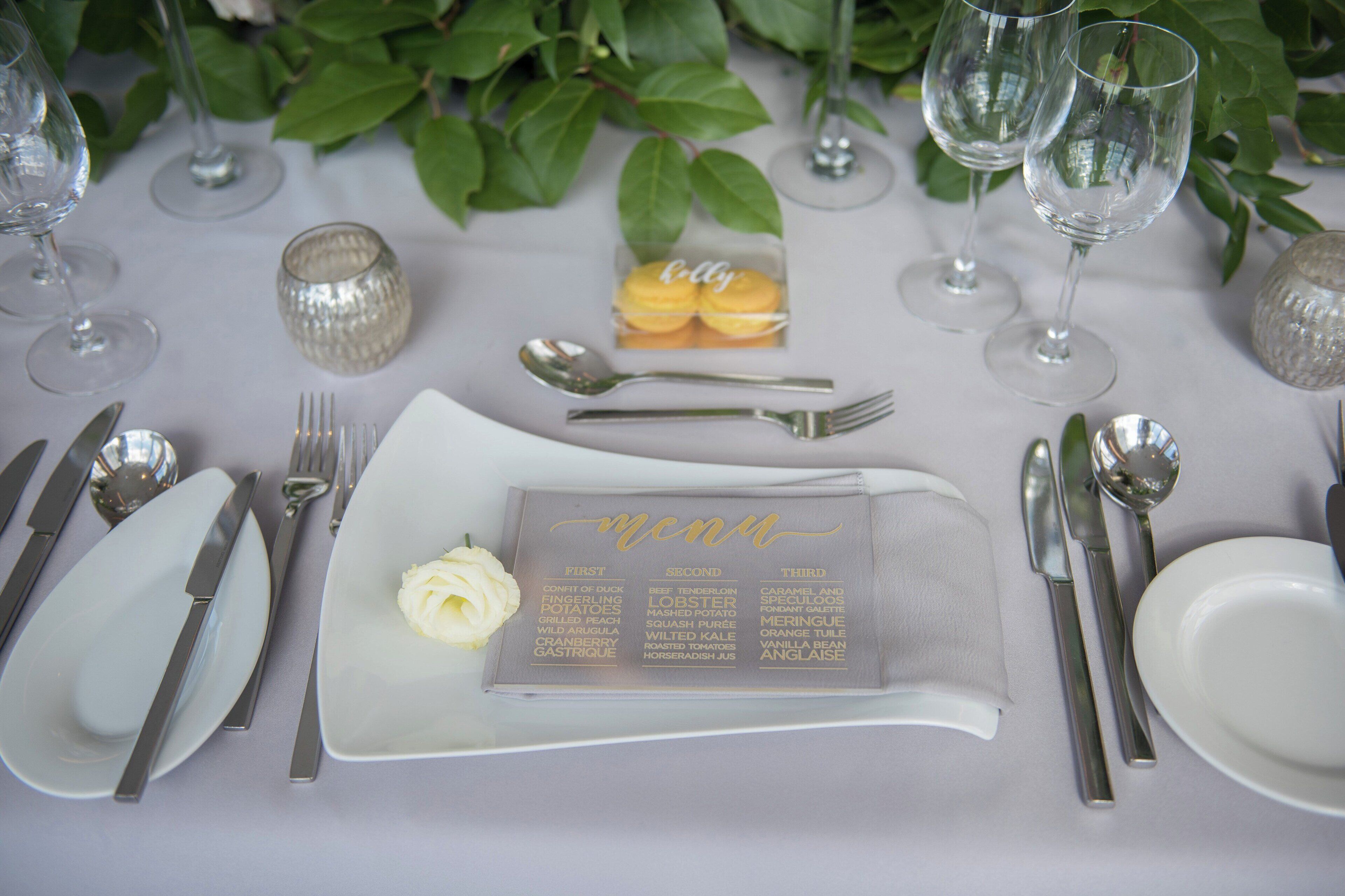 A table set with fine dining utensils, a menu, and a small decorative item.