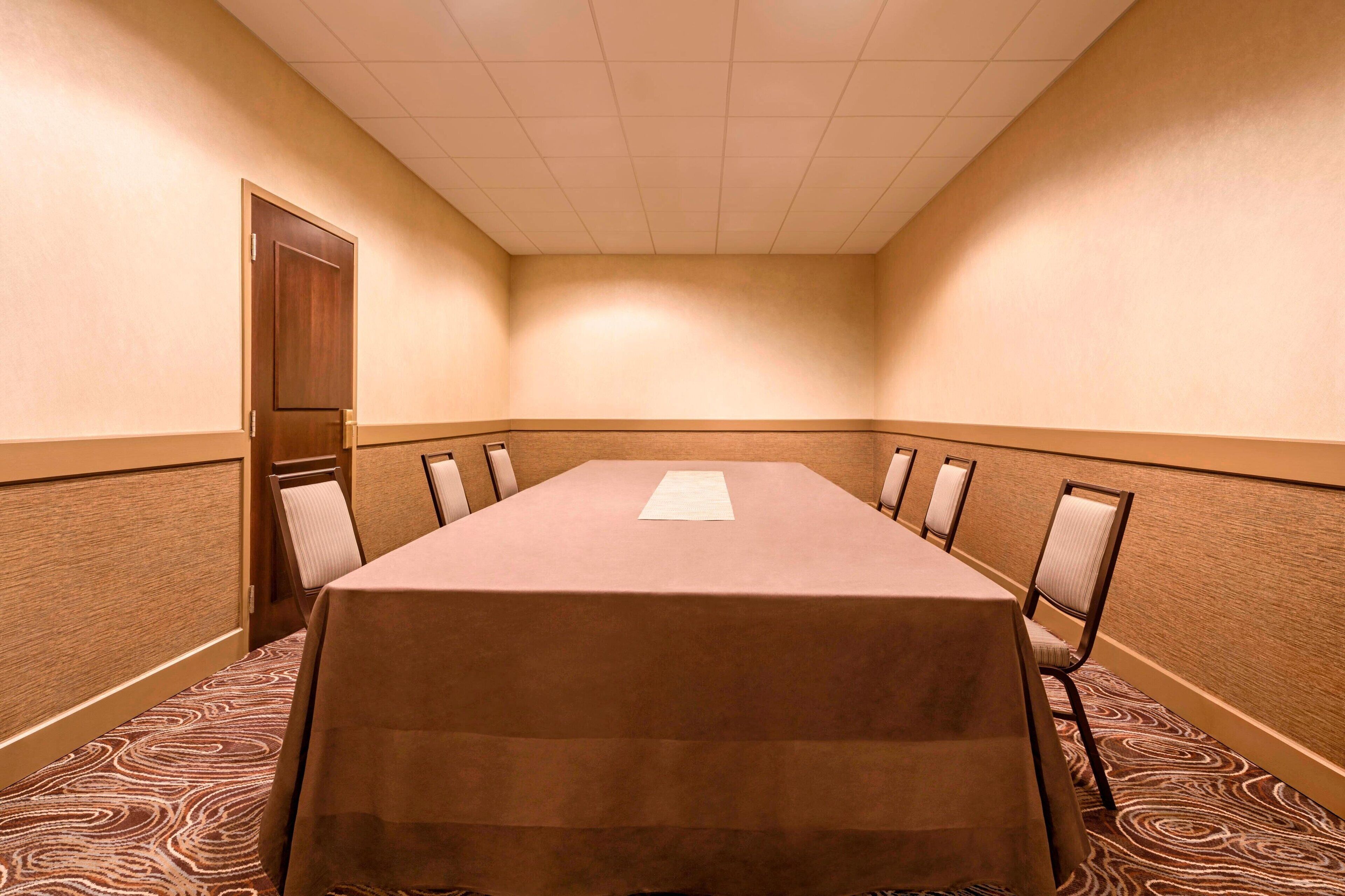 A conference room with a long table, chairs, and a door.