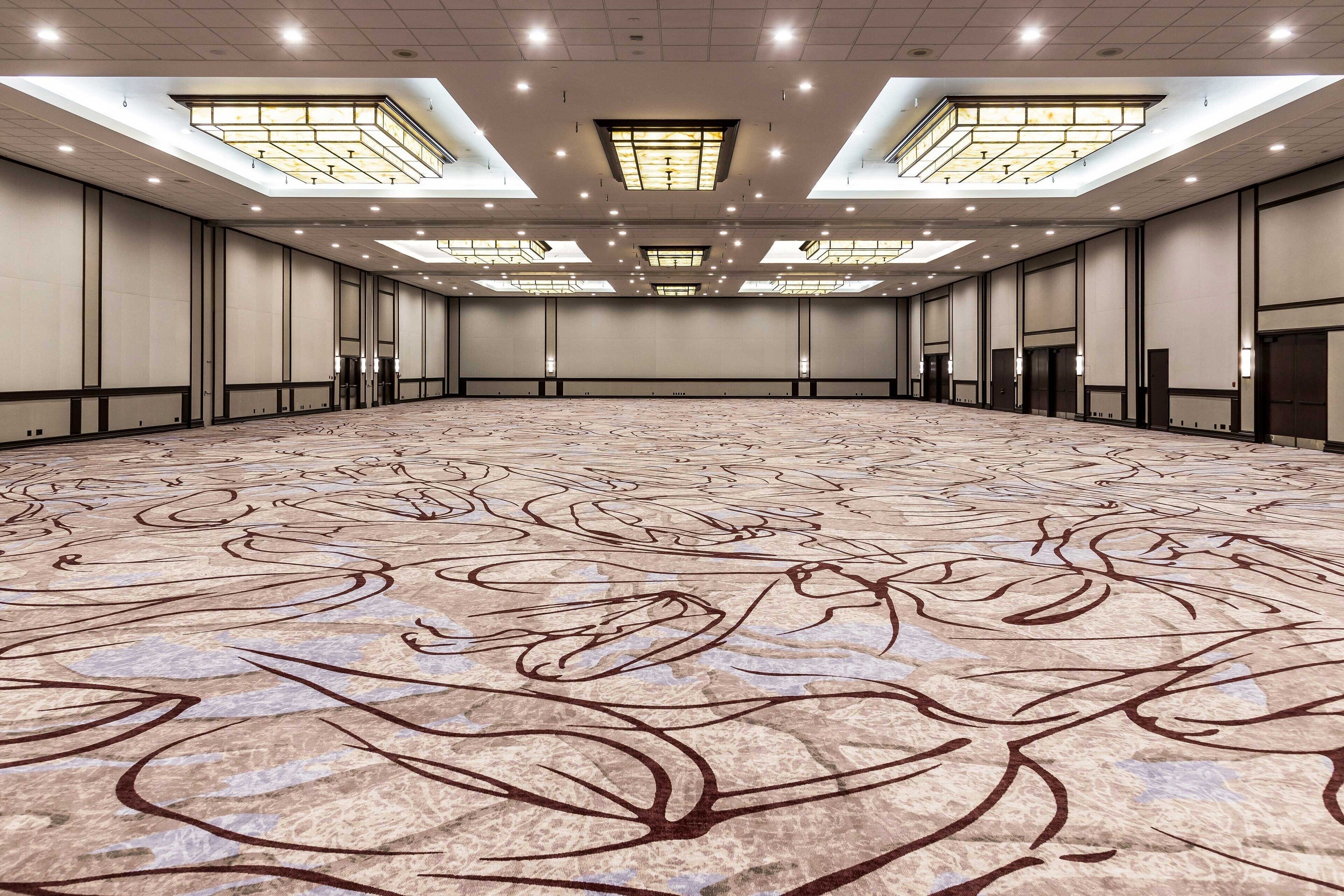A large, empty conference room with a patterned carpet, high ceilings, and skylights.