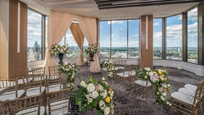 Montaje de ceremonia de boda con vistas a la ciudad, que incluye un escenario con arreglos florales y sillas dispuestas para los invitados.