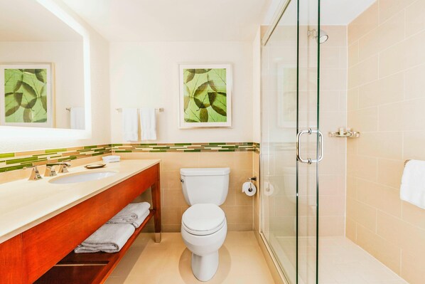 Un baño moderno con cabina de ducha de vidrio, lavamanos dobles y un inodoro.