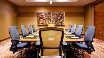 A conference room with a long table, chairs, and two large abstract paintings on the wall.