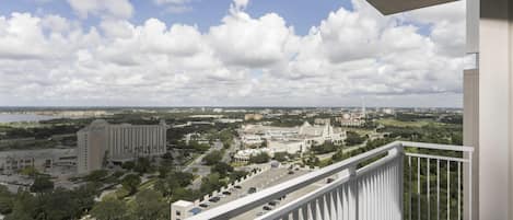 A balcony with a view of a cityscape, including buildings and greenery.