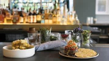 Un bar con un plato de comida, un bol de papas y una ensalada.