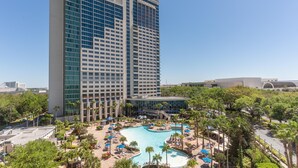 A high-rise hotel with a swimming pool, palm trees, and a clear blue sky. - Hyatt Regency Orlando (Orlando)
