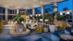 A spacious lobby with a central bar area, multiple seating arrangements, and large windows offering views of the cityscape. - Hyatt Regency Orlando (Orlando)