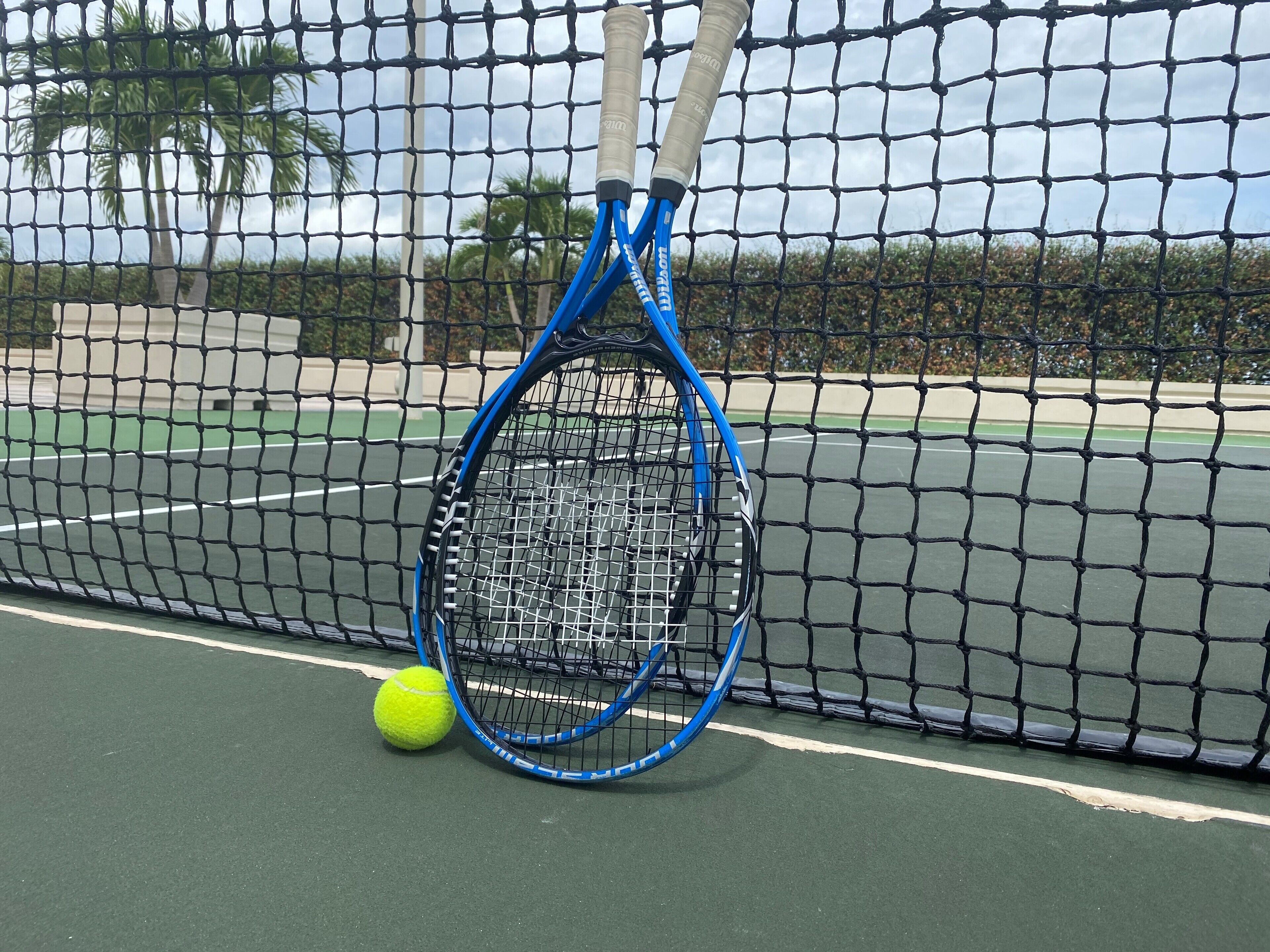 Un campo da tennis con rete, racchetta e pallina.
