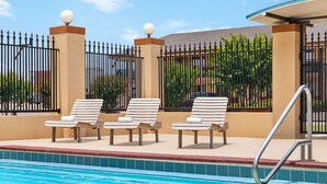 A swimming pool with lounge chairs and a metal ladder. - Days Inn by Wyndham Paris (Paris)