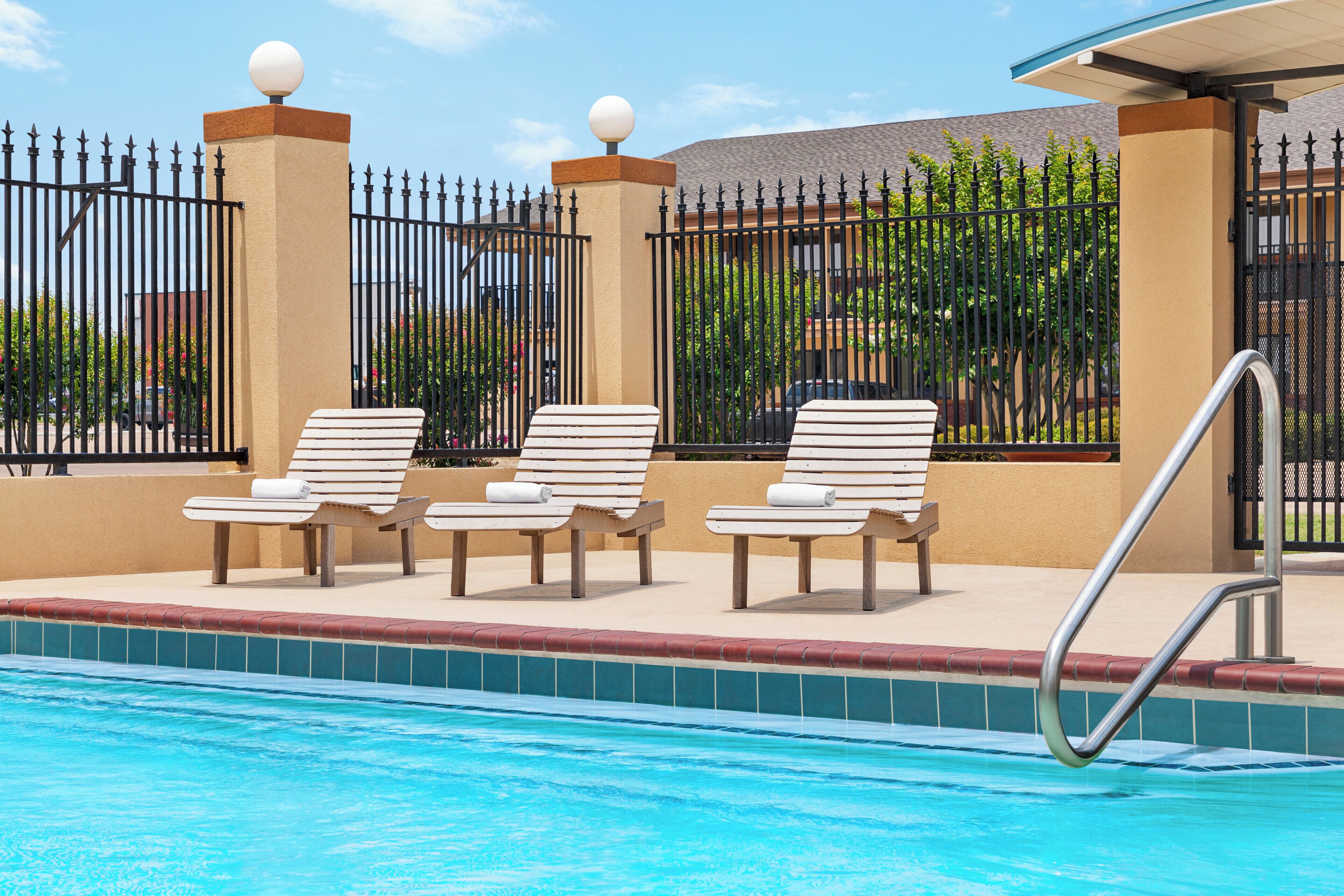 A swimming pool area with lounge chairs and a metal pool ladder.