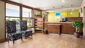 A reception area with a wooden reception desk, a potted plant, and a seating area with patterned chairs. - Days Inn by Wyndham Paris (Paris)