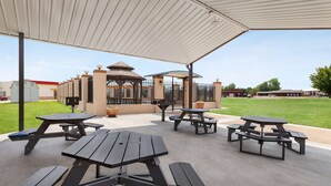 An outdoor patio area with picnic tables and a covered seating area. - Days Inn by Wyndham Paris (Paris)