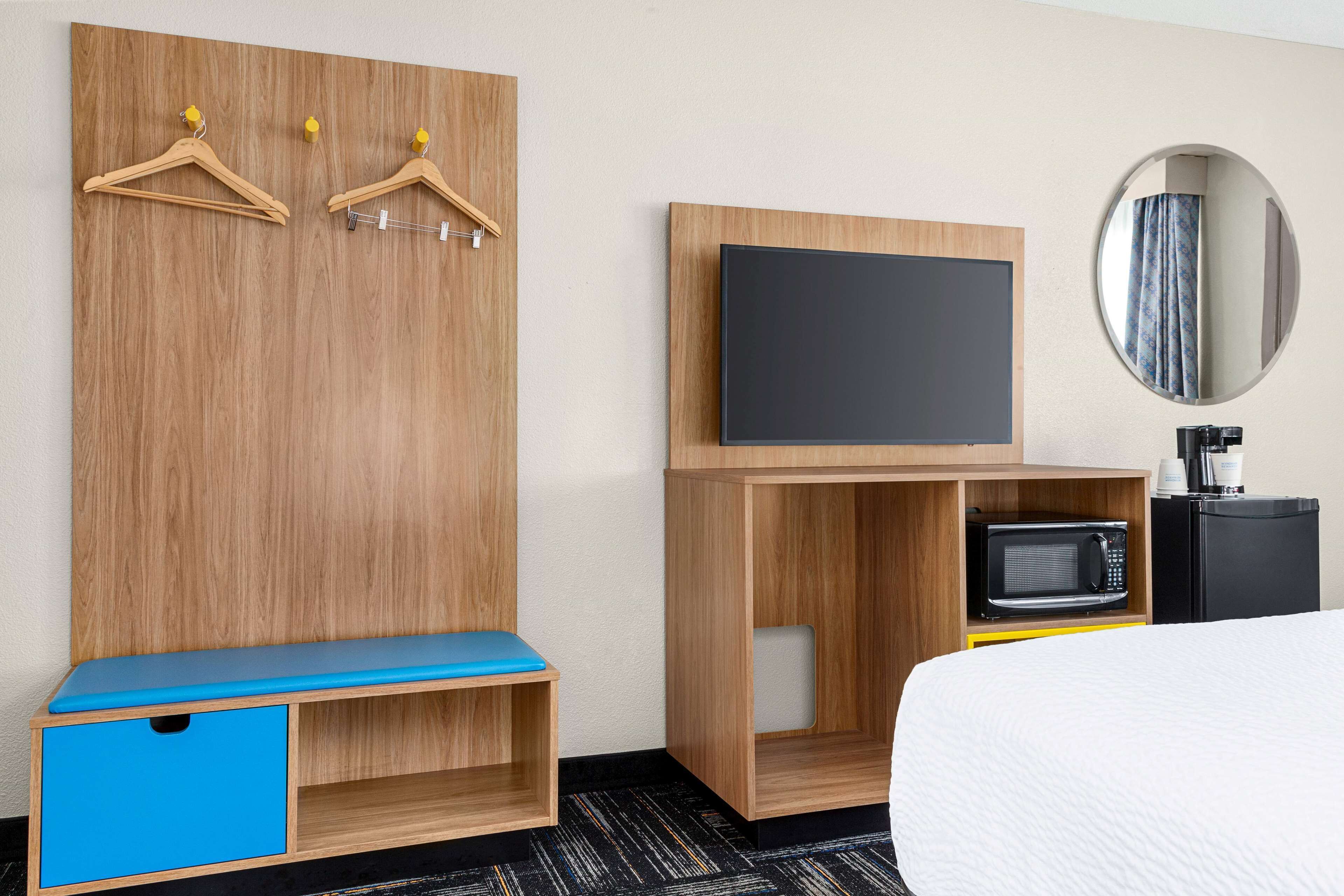 Een hotelkamer met een houten garderobe, een flatscreen televisie, een magnetron en een bed.