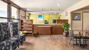 A hotel lobby with a reception desk, seating area, and a plant. - Days Inn by Wyndham Paris (Paris)