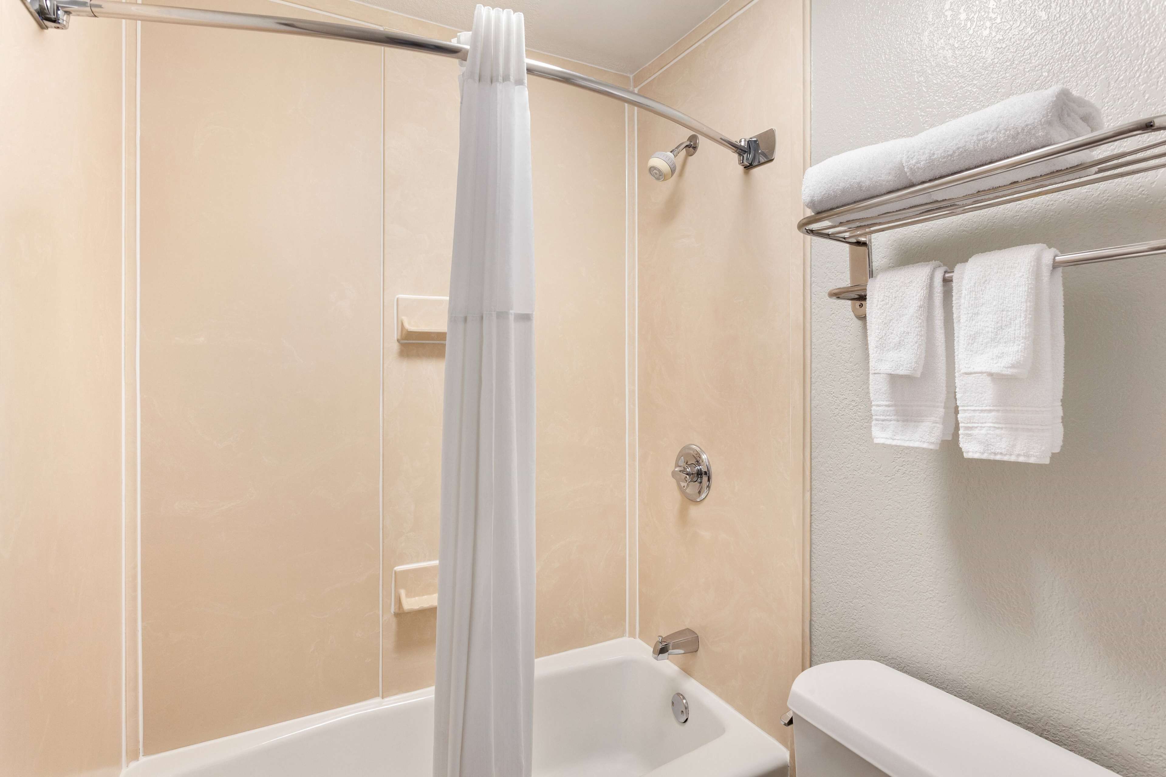 Un baño con una bañera, una cortina de ducha y un perchero con dos toallas.