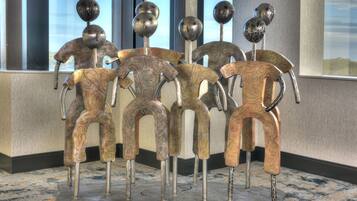Ein Zimmer mit einem gemusterten Teppich, einem großen Fenster und einer dekorativen Metallskulptur.