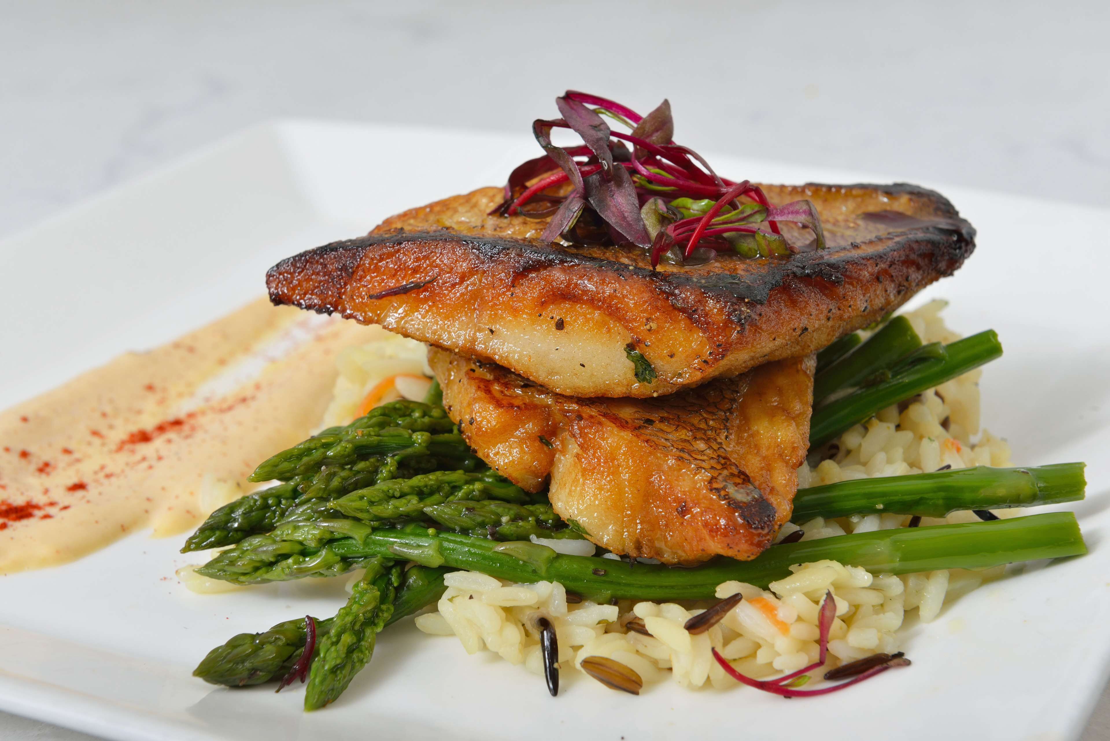 Une assiette de poisson grillé, d’asperges et de riz.