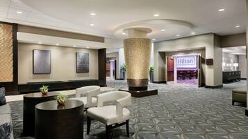A spacious lobby with a central column, seating area, and a visible Hilton sign.